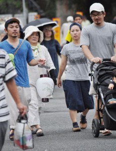 ちょうちんを手に先祖の霊を自宅に導く人々＝３日、奄美市名瀬の永田墓地