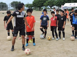 子どもたちに指導する鹿児島Ｕの新中さん（左）＝１５日、喜界町総合グラウンド