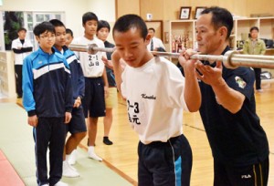 池畑さん（右）のアドバイスを受けながらスクワットトレーニングを体験する生徒＝１１日、名瀬中学校