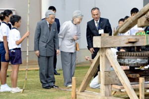 黒糖づくりに使うサタグルマをご覧になる天皇、皇后両陛下＝１８日午前１１時２１分、和泊町国頭の国頭小学校（代表撮影）