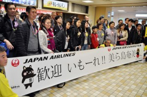 歓迎セレモニーで記念撮影するシンガポールからのツアー客ら＝２４日、奄美空港