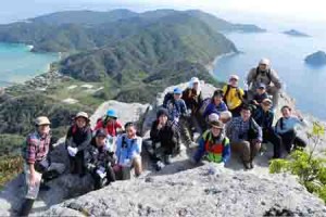 ミヨチョン岳の絶景を背景に記念撮影する参加者＝１０日、瀬戸内町請島（同町提供）