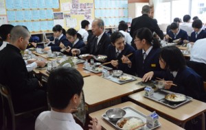  福山副市長（中央）と魚汁や豚みそなどの郷土料理を給食で楽しむ生徒たち＝２３日、奄美市の朝日中学校