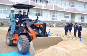 建設機械の操縦を体験する生徒＝１９日、知名中学校グラウンド