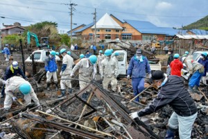 力を合わせて火災現場を片付ける住民ら＝３日、奄美市笠利町