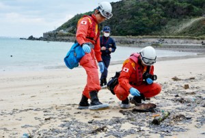 油状の漂着物を調査する機動防除隊ら＝２日、奄美市名瀬の朝仁海岸