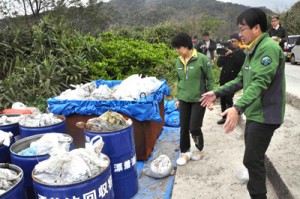 回収された漂着油について説明を受ける渡嘉敷環境副大臣（左）＝１４日、奄美市名瀬の朝仁海岸