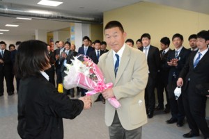 歓迎の花束を受け取る佐々木監督＝１７日、奄美空港