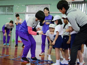 ランニング教室で児童と交流する東北福祉大陸上部の選手たち＝２１日、田検小