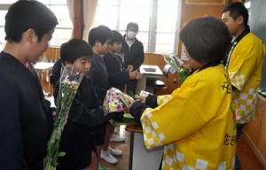 小学生にスプレーギクの花束を贈る研究会のメンバーら＝２日、和泊町の内城小
