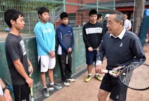 高校生にラケットの構え方をアドバイスする坂井さん（右）＝１０日、奄美市の名瀬運動公園庭球場