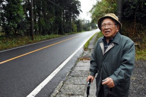 与論島出身者が暮らしていた「よろん坂」に立つ箕作永吉さん＝６日、屋久島町