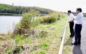 ヘリから落下したカーゴドアが発見された草地付近を確認する知名町職員＝７日午前１０時半ごろ、同町の山田ダム近く