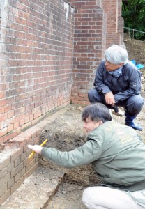 久慈水溜跡のれんがを調査する山岡さん（手前）と鼎さん＝６日、瀬戸内町