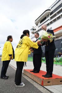 谷会長（後方左）らから花束を受け取るターナー船長ら＝１３日、奄美市名瀬港観光船バース 