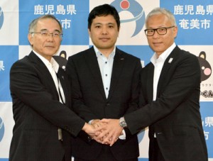 市の職員として㈱ＮＴＴドコモから派遣された竹山さん（写真中央）と東副市長（同左）、有田部長＝２６日、奄美市