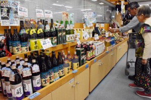 奄美黒糖焼酎を手に取る買い物客＝１２日、菊池市の特産品センター「七城メロンドーム」 