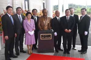 開館した徳田虎雄顕彰記念館（上）と徳田氏の銅像を囲み開館を祝う関係者＝２８日、徳之島町亀徳