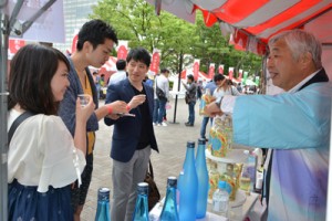 来場者へ奄美黒糖焼酎の説明をする蔵元＝１６日、東京都   