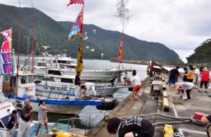 船上からの餅投げに歓声が上がった山間集落の浜下れ行事＝３日、奄美市住用町の山間港