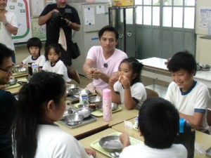 満島さん（中央）と給食を楽しむ薩川小の子どもたち＝１９日、瀬戸内町