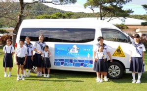 スクールバスを前に記念撮影する伊子茂小中の子どもたち＝１２日、瀬戸内町加計呂麻島の同校
