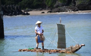 琉球列島間の交易や移住で使われた舟の検証で筏舟の進水実験をする日本工業大学特別研究員の基さん＝２２日、天城町の平土野漁港  