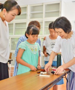 増田さん（写真右）から紬の髪飾り作りを教わった参加者たち＝２８日、奄美市名瀬浦上町の奄美市産業支援センター