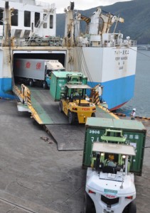  次々に運び出される食料品などを満載したコンテナと車両＝２４日、奄美市の名瀬港