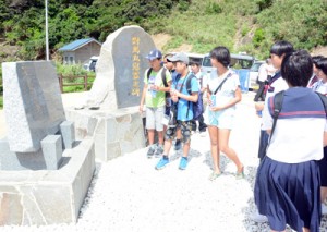 対馬丸について記された碑文を読む沖縄県と宇検村の小中学生＝１８日、宇検村の船越海岸