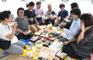 墓前で一重一瓶を囲んで先祖の霊を送る一族＝１５日、徳之島町亀津