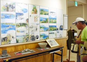 住民の話を文章入りで描いた水彩画が並ぶ証言記録展＝１日、姶良市の姶良公民館