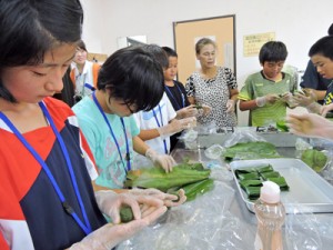 真剣な表情でもちを包む子どもたち＝７日、喜界町中央公民館