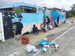 壁画の修復作業を行う徳之島高校美術部の現役部員とＯＧら（提供写真）