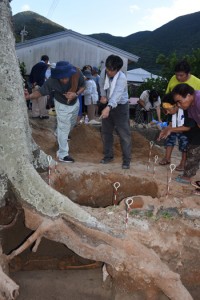 出土した人骨（左下）と住民らに説明する竹中教授（中央）＝１５日、宇検村屋鈍