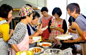 講師の福山さん（右）から調理のこつを教わる参加者＝８日、奄美市名瀬