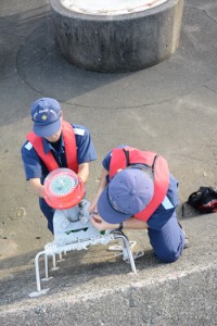 仮灯火を設置する奄美海保の職員。後方にある円形の土台が消失灯台のあった場所＝６日、奄美市の名瀬港西防波堤