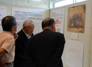 大正時代に村で撮影された貴重な写真に見入る企画展開幕式の出席者＝２２日、宇検村の元気の出る館