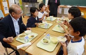 竹田町長（左）と地場産米を使った給食を味わう秋名小児童ら＝１１日、龍郷町