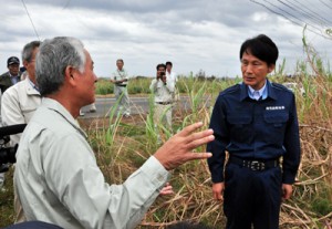 サトウキビの被害状況などについて説明を受ける三反園訓知事（右）＝１２日、奄美市笠利町