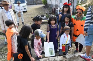 写真などをヒントに、工場の基礎に使われていた白糖石（凝灰岩）を見つけた小学生ら＝２８日、瀬戸内町久慈