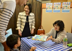 絵本「ケンムンとぼくの夏」を手渡す作者の永田萠さん（写真右）＝１１日、宇検村湯湾