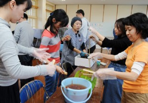 佐田さん（中央）の指導の下、イトバショウの繊維取りを体験する受講生ら＝２４日、瀬戸内町俵