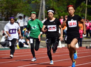 【４０代女子１００㍍】力走する各地区の選手たち＝１１日、奄美市名瀬運動公園陸上競技場