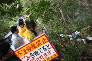 山間部に捨てられた衣類など家庭ごみを確認する参加者＝２１日、奄美市名瀬