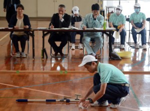 審査員の前で清掃作業を行う受検者＝１２日、龍郷町の県立大島養護学校体育館