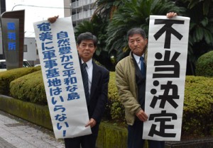 福岡高裁宮崎支部の判断を受けて「不当決定」と書いた紙を掲げる城村さん（右）ら＝１１日、宮崎市の福岡高裁宮崎支部前