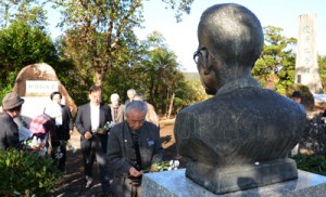 泉芳朗の胸像に献花する参加者＝２５日、奄美市名瀬のおがみ山公園