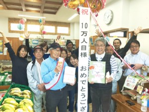 「加計呂麻島のいっちゃむん市場」１０万人目の来場者となった髙橋司さん（前列左）＝１９日、瀬戸内町（提供写真）