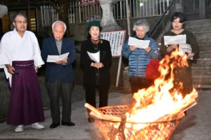 かがり火を囲んで日本復帰の歌を歌う参加者たち＝２５日、奄美市名瀬の高千穂神社